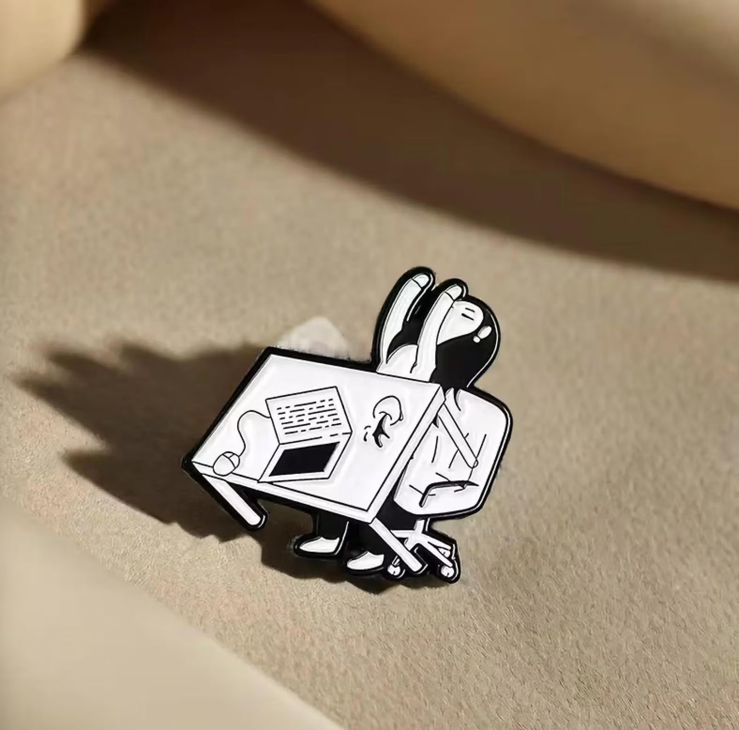 A cartoon-style enamel pin of a rabbit sitting at a desk reading, displayed on a wooden tray with miniature books and stationery props. Work and Study Enamel Pin, Cute Student Laptop and Books Pin, Kawaii School Accessory, Black & White Brooch, Backpack Gift, Desk Decor